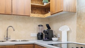 Eine moderne Küche mit Holzschränken, einer Spüle, einer Kaffeemaschine und einem eingebauten Herd.