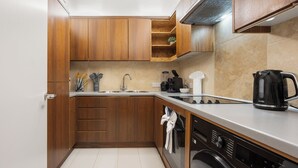 Eine kleine Küche mit Holzschränken, einer Edelstahlspüle, einer Kaffeemaschine und einem Geschirrspüler.