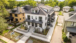 Ein modernes, zweistöckiges Haus mit flachem Dach, großen Fenstern und einem angelegten Vorgarten.