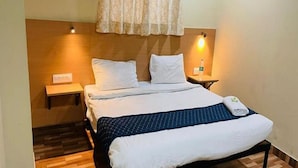 A neatly arranged hotel room with a bed, two bedside tables, a wooden floor, and a window with a curtain. - Hotel Jeet Stay  (New Delhi)