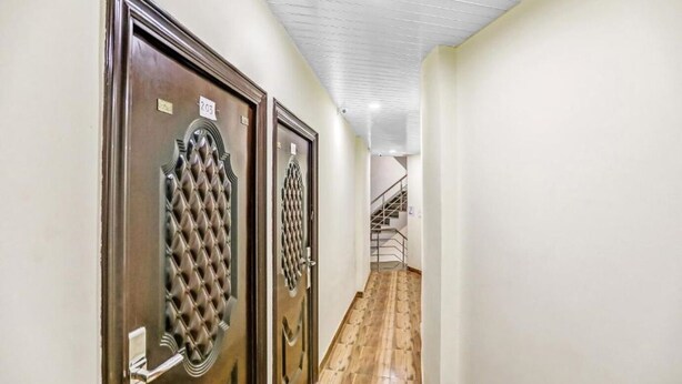 A hallway with two doors, wooden flooring, and a staircase in the background. - Hotel Jeet Stay  (New Delhi)