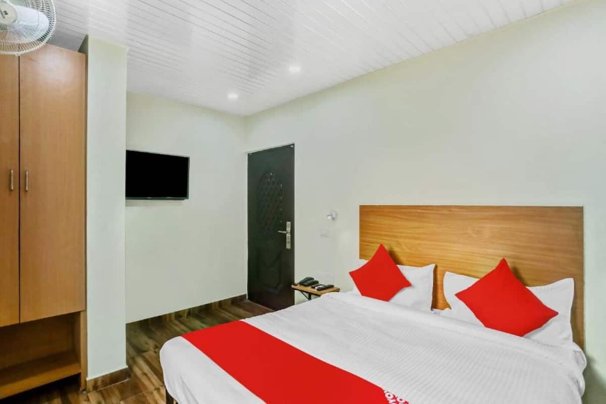 A hotel room with a bed, a wardrobe, a television, and a door.