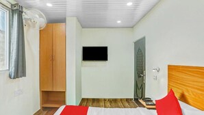 A bedroom with a bed, a TV, a wardrobe, and a door. - Hotel Jeet Stay  (New Delhi)