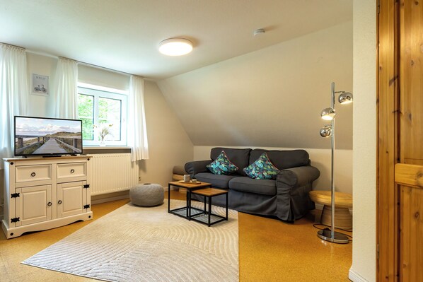 A living room with a television, sofa, and a small table. - Hier Spielt ein Echter Naturbursche die Erste Geige: Eichenholz (Morsum)