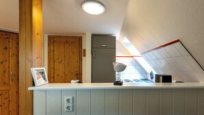 Une cuisine avec des meubles de rangement en bois, un plan de travail blanc, un luminaire au plafond et une petite sculpture d’oiseau.