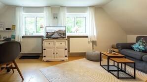 Un salon avec un téléviseur, un canapé et une table basse.