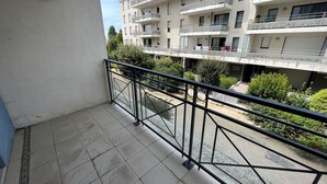 A balcony with a metal railing, a tiled floor, and a view of a multi-story building with balconies. - Cozy 1BR Apartment with Balcony and Garage Near Beach and Downtown (Les Sables-d'Olonne)