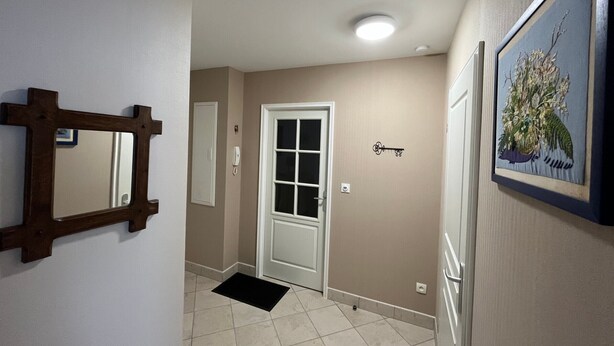 A hallway with a door, a mirror, a light fixture, and a framed picture on the wall. - Cozy 1BR Apartment with Balcony and Garage Near Beach and Downtown (Les Sables-d'Olonne)