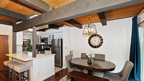 A modern kitchen with white cabinets, stainless steel appliances, and a wooden ceiling.