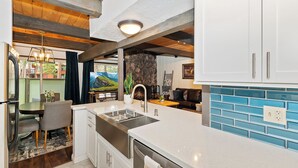 A modern kitchen with white cabinets, a blue backsplash, and a stone accent wall.