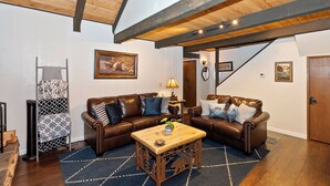 A cozy living room with two leather sofas, a wooden coffee table, and a patterned rug.