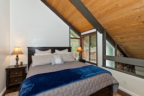 Une chambre à coucher avec un lit, des tables de chevet et un plafond en bois.