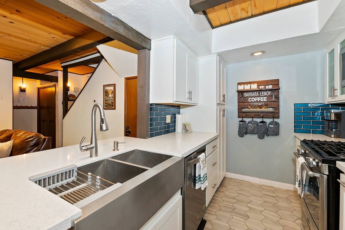 A modern kitchen with a central island, stainless steel appliances, and a blue-tiled backsplash.