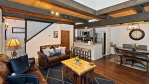A spacious living area with a brown leather sofa, a wooden coffee table, and a kitchen in the background.