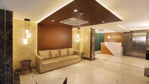A modern lobby with a sofa, a reception desk, and an elevator. - Aralia International Airport Mumbai (Mumbai)