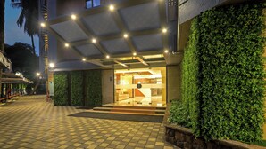 A hotel entrance with a checkered tile floor, a covered entrance area, and a green hedge on the right. - Aralia International Airport Mumbai (Mumbai)