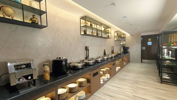 A modern hotel buffet with a long counter, various food stations, and neatly arranged plates and bowls. - Aralia International Airport Mumbai (Mumbai)