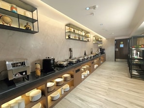 A modern hotel buffet with a long counter, various food stations, and neatly arranged plates and bowls. - Aralia International Airport Mumbai (Mumbai)