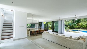 Un espace de vie moderne comprenant un coin repas, un grand canapé et une vue sur une piscine.
