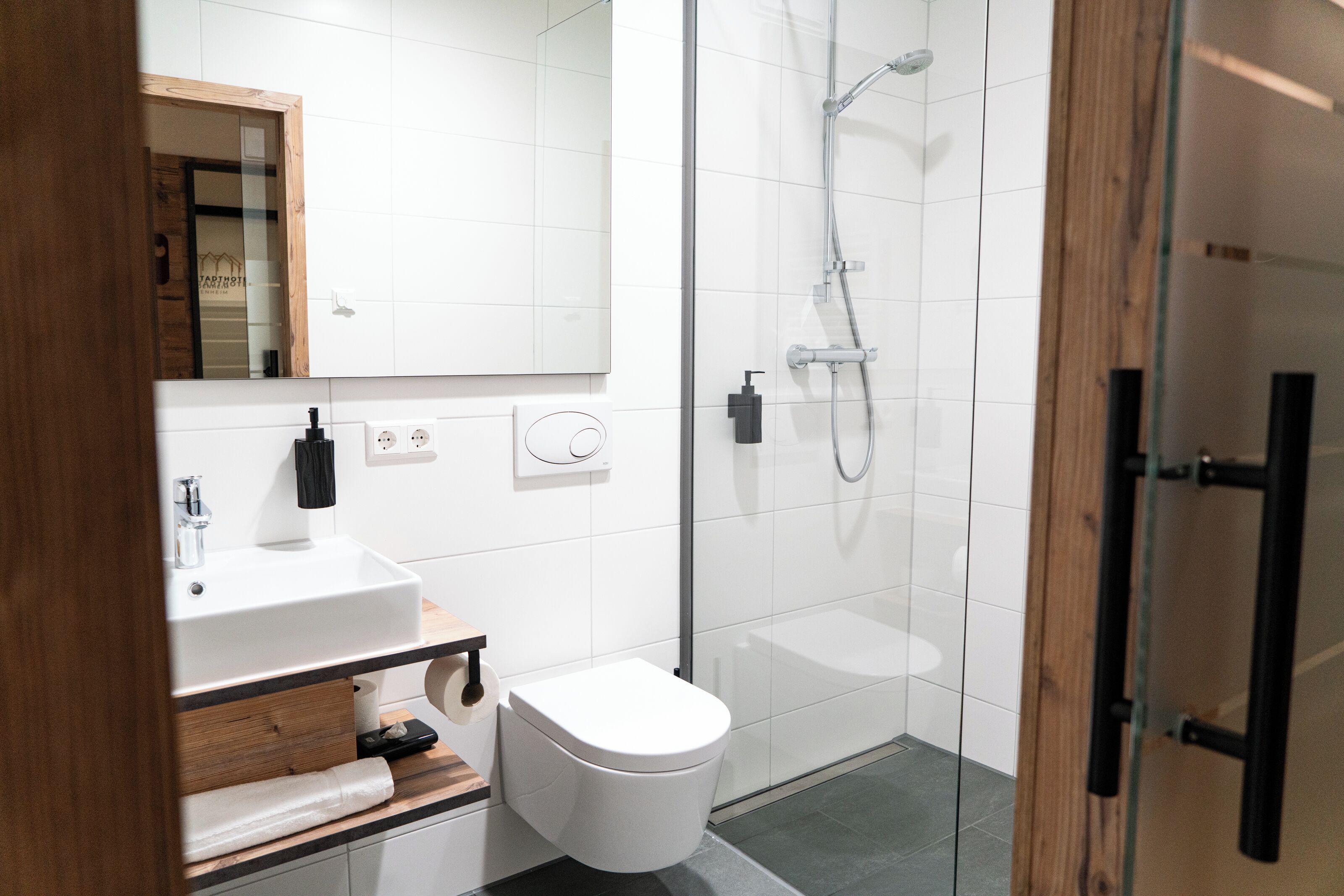 Une salle de bain moderne avec un lavabo blanc, des toilettes et une douche à parois de verre.