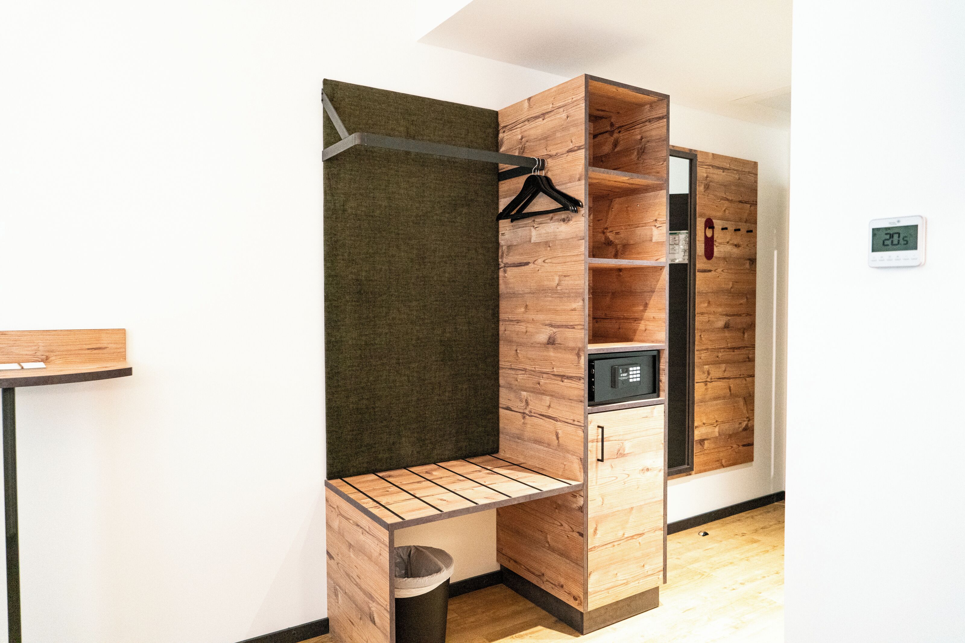 A modern room with a built-in wooden wardrobe, a small bench, and a wall-mounted heater.