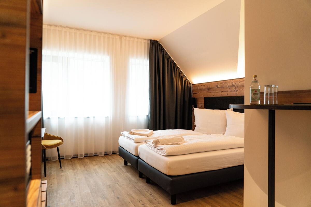 Een hotelkamer met een bed, een stoel, een bureau en een raam met gordijnen.