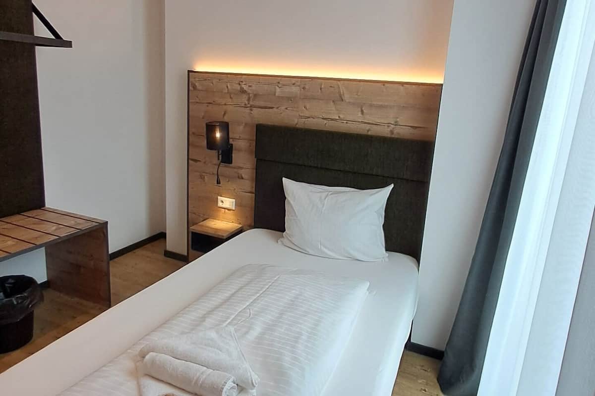 Een hotelkamer met een bed, een nachtkastje, een wandlamp en een houten hoofdeinde.