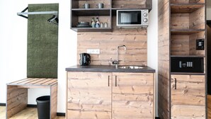 Een compacte keuken met houten kastjes, een ingebouwde magnetron en een klein spoelbakje.