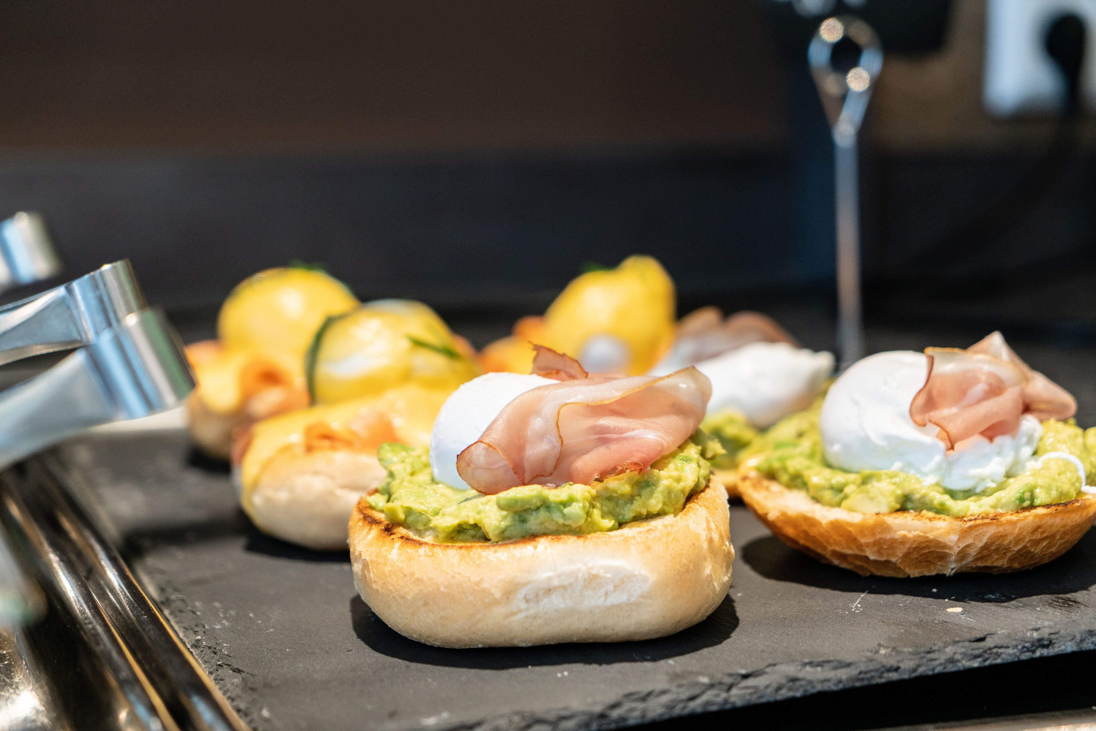 Ein reichhaltiges Frühstücksbuffet mit Avocado-Toast, pochierten Eiern und Prosciutto.