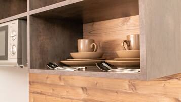 A kitchen with wooden cabinets, a microwave, and stacked beige dishes.