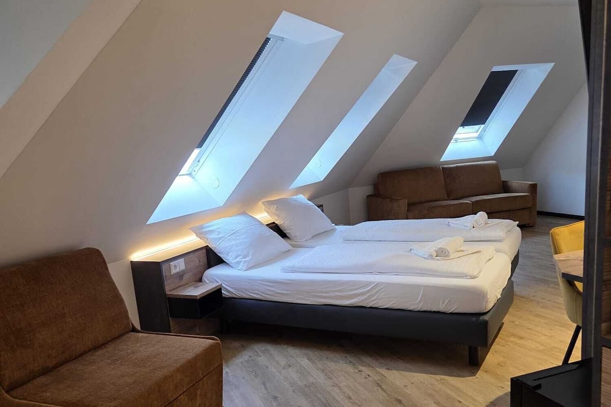 Een moderne loft slaapkamer met een groot bed, een bank en een eettafel.
