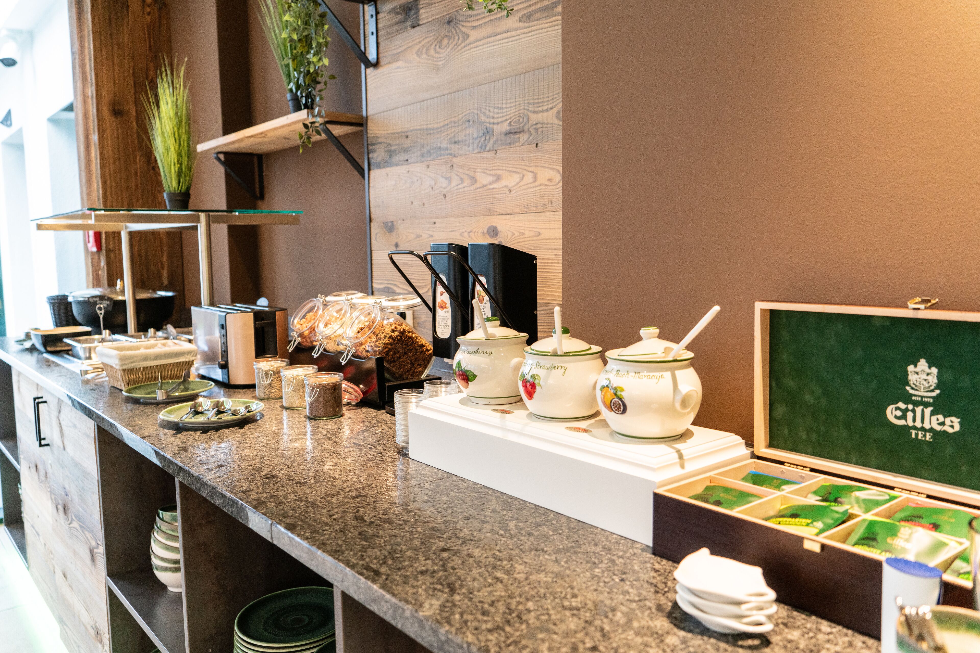 Mostrador de buffet con diferentes alimentos, recipientes de té y una presentación de tés.