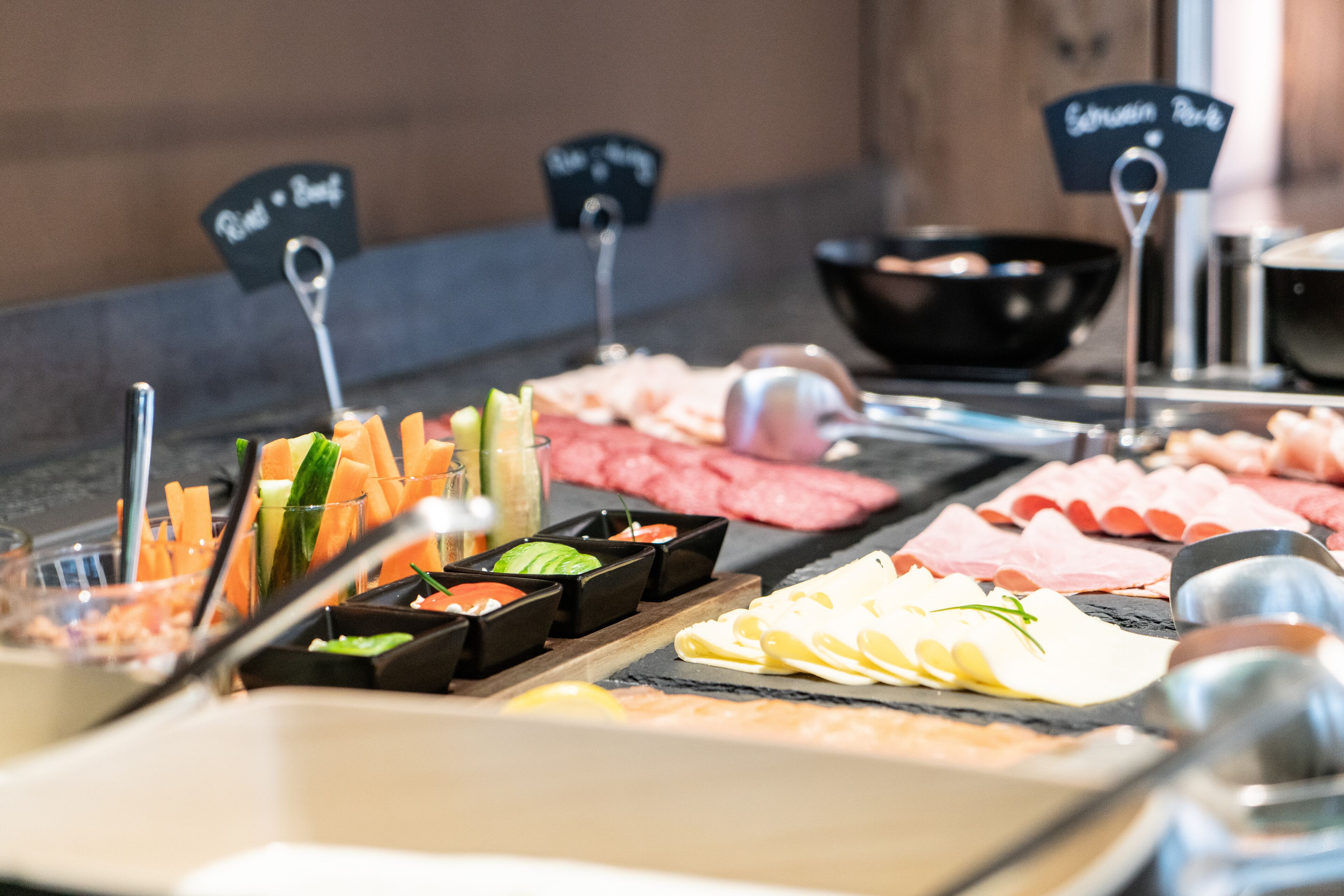 A buffet with various meats, cheeses, and vegetables.