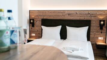 Una cama doble bien hecha con sábanas blancas, un cabecero de madera y dos lámparas de noche.