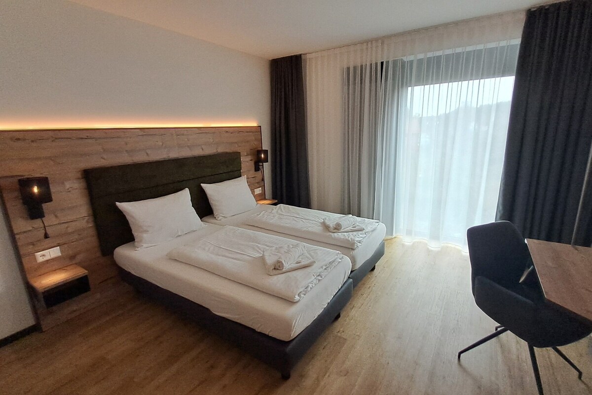 Een hotelkamer met twee bedden, een bureau en een stoel.