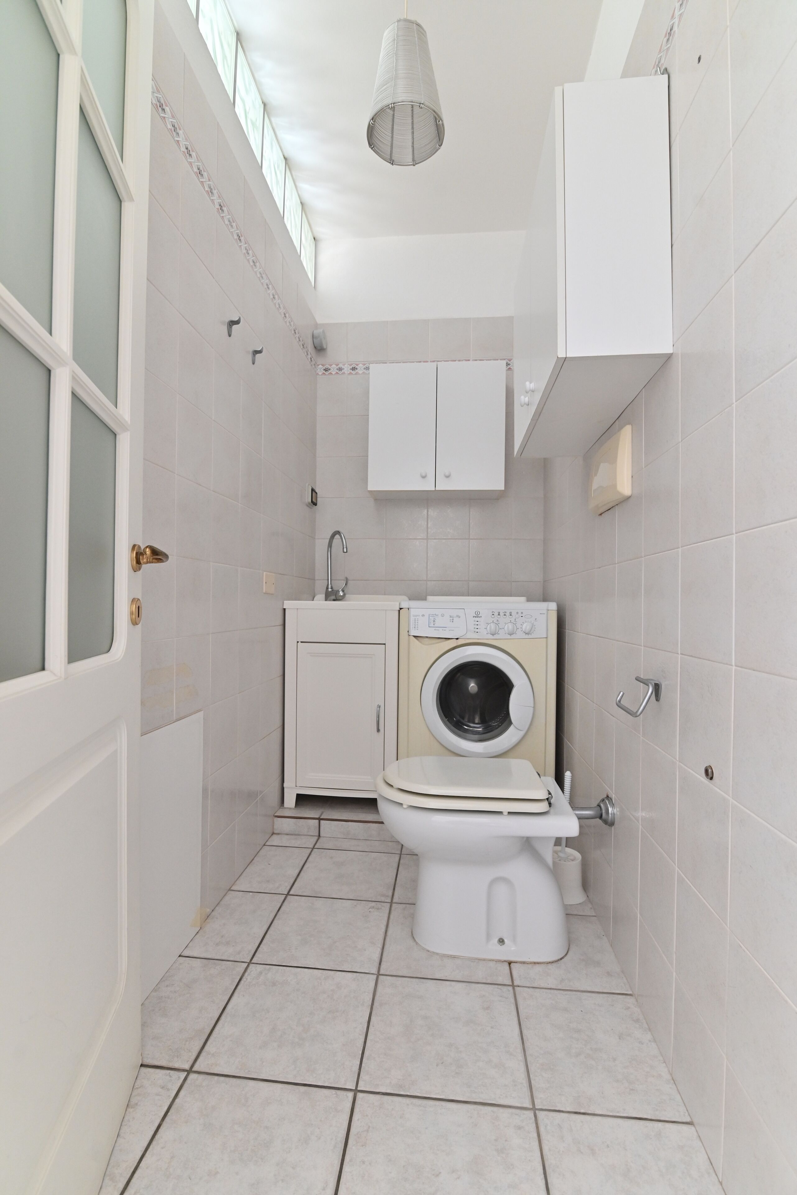 Un baño pequeño con inodoro, lavadora y lavamanos.
