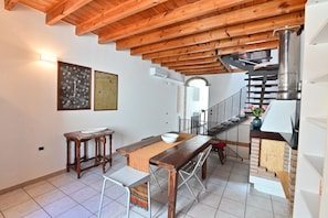 A dining area with a wooden table, chairs, and a bench. There is a staircase with a metal railing leading to an upper floor. - IzzHome Full Center Terrace (Cagliari)