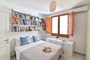 A bedroom with a bed, a bookshelf, a window with wooden shutters, and a tray with a book and a cup. - IzzHome Full Center Terrace (Cagliari)