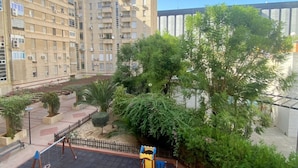 A residential building with multiple balconies, a playground, and surrounding greenery. - Rentalsevilla en Nervión (Sevilla)
