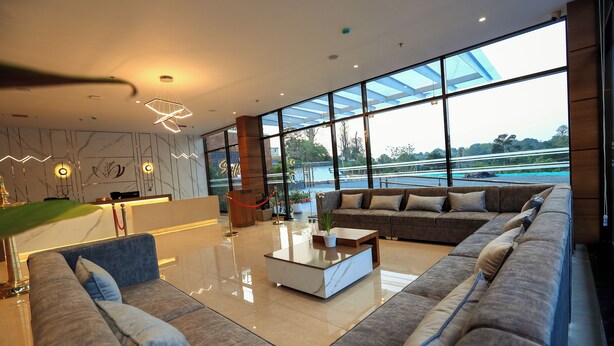 A modern hotel lobby with a large sofa, a coffee table, and a reception desk. - Hotel Saffron Wayanad (Sulthan Bathery)