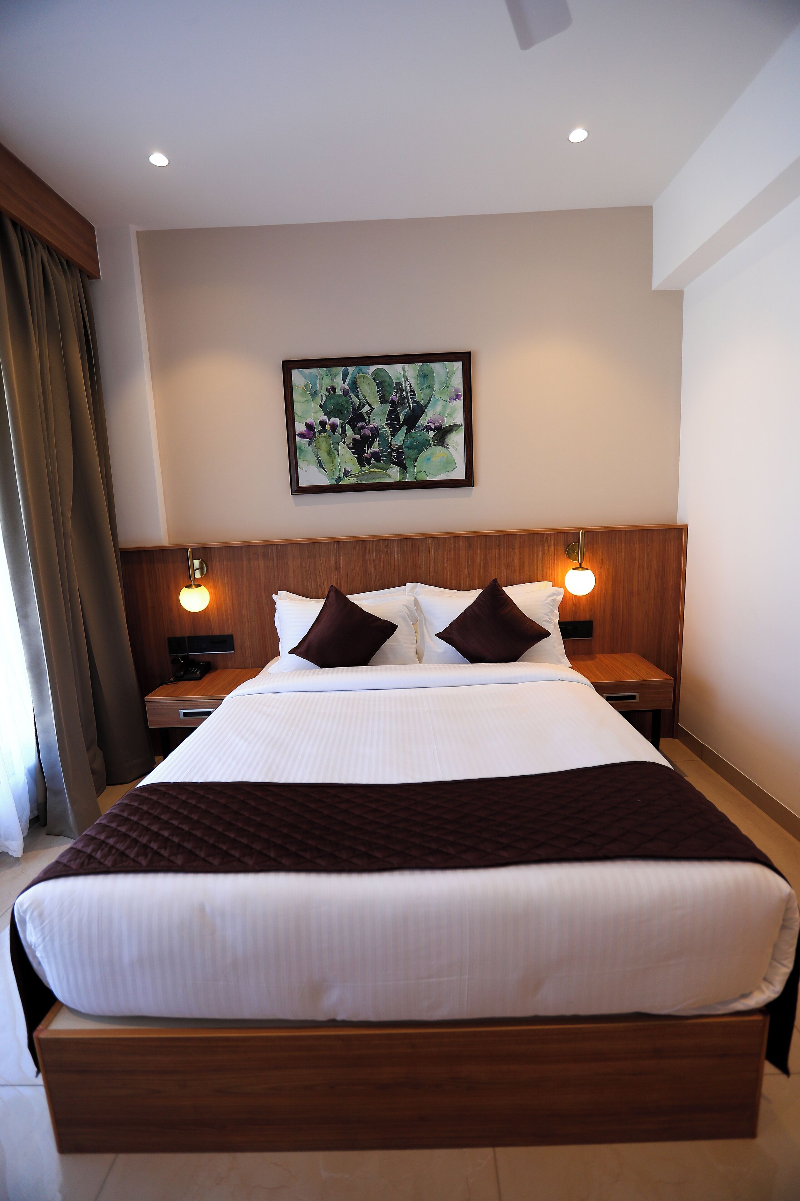 Ein Hotelzimmer mit einem großen Bett, zwei Nachttischen, einem Wandbild und einer Deckenleuchte.