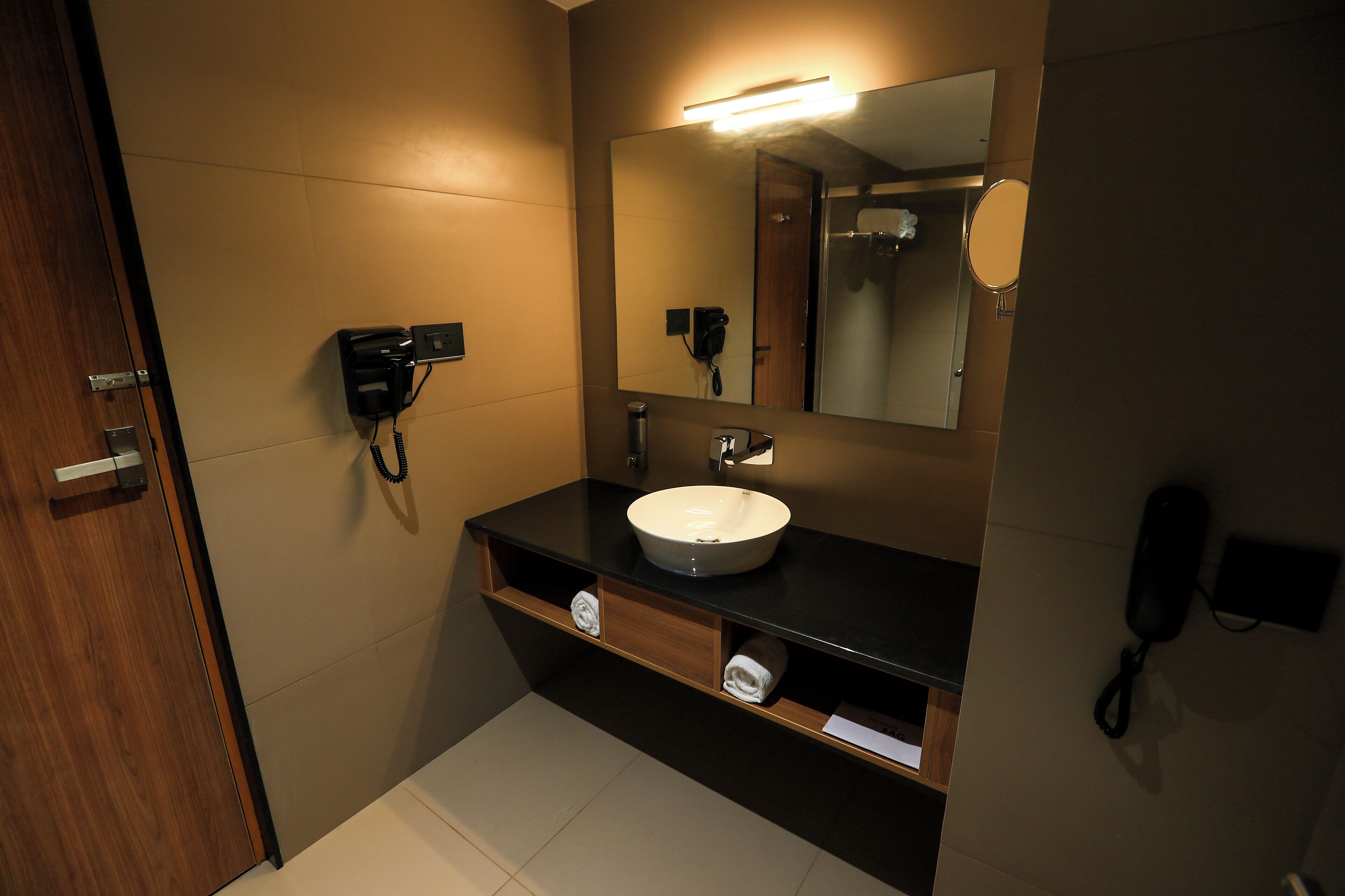 Un baño moderno con un espejo grande, un lavabo y un secador de pelo.