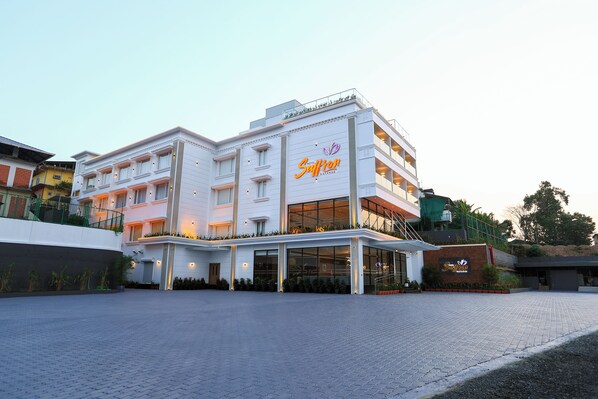 Un hotel moderno con un letrero llamativo, varios pisos y un área de entrada pavimentada.