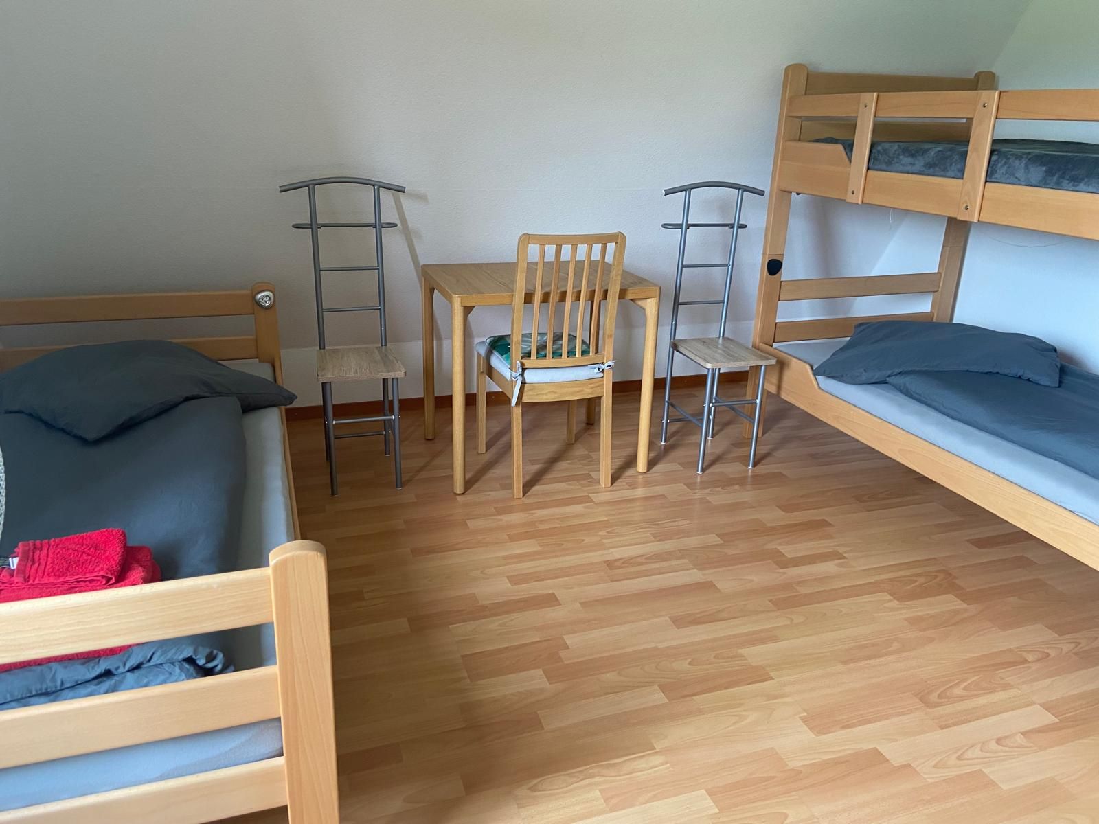 Una stanza con un letto a castello, una scrivania con due sedie e un pavimento in legno.