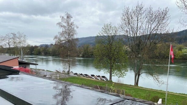 Aussicht auf einen Fluss mit einer roten Flagge, einem Gebäude und Booten.