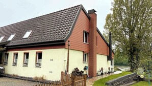 Ein zweistöckiges Gebäude mit einem geneigten Dach, einem Ziegelkamin und mehreren Fenstern.