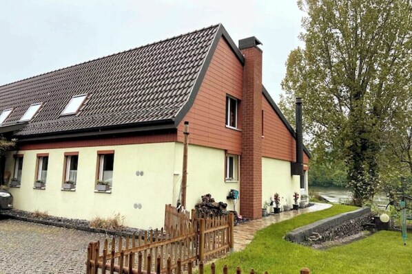 A two-story building with a sloped roof, a brick chimney, and multiple windows. - Vacation apartment on the Rhine (Sisseln)