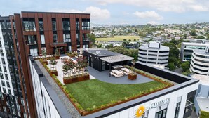 A rooftop garden with seating areas and a view of the cityscape. - Ellerslie Sanctuary | Luxury Apt & Great Amenities (Auckland)