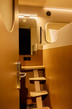 A compact, modern bathroom with a wooden finish, a built-in sink, and a mirror. - Kabannas London St Pancras (London)