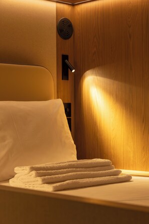 A hotel room with a bed, a wall-mounted heater, and a control panel. - Kabannas London St Pancras (London)